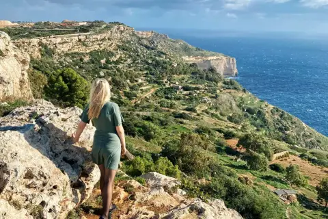 Malta w listopadzie: kobieta podziwia malownicze klify i morze. Pogoda sprzyja spacerom po zielonych wzgórzach.