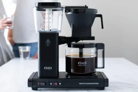 Czarny ekspres do firmy Techni Vorm Moccammaster z dzbankiem pełnym kawy. Idealny do biurowych poranków.