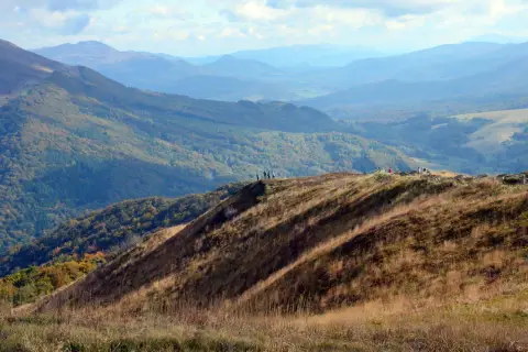 Widok na Bieszczady Połonina Wetlińska. Grupa turystów podziwia jesienne krajobrazy górskie.