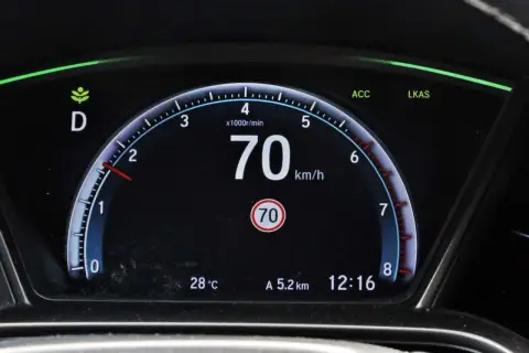 Cyfrowy prędkościomierz samochodu pokazuje 70 km/h, obok wskaźnik temperatury i zegar.