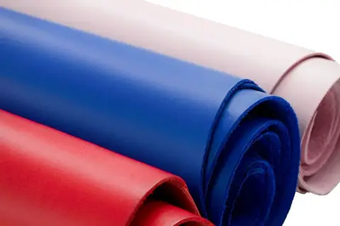Rouleaux de cuir coloré, rouge, bleu et rose pâle, évoquant la douceur d'une vachette animal.