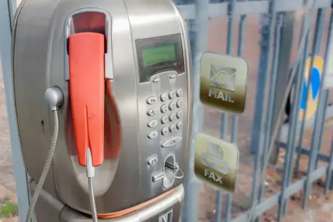 Stary unifon z pomarańczową słuchawką, obok ikony poczty i faksu.