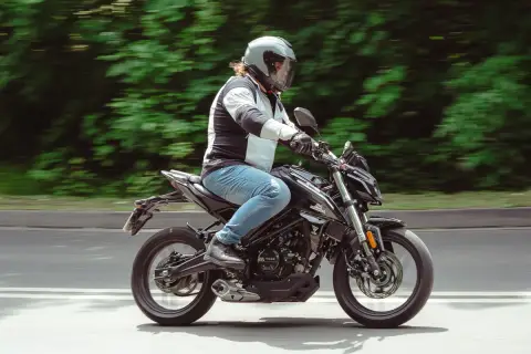 Mężczyzna w kasku jedzie czarnym motocyklem. Idealny motor na kat B, by poczuć wolność na drodze.