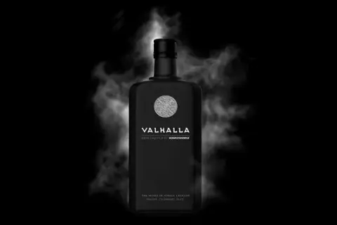 Czarna butelka Valhalla, ziołowego likieru, otoczona mgłą. Poczuj ducha nordyckich legend z tym wyjątkowym alkoholem.