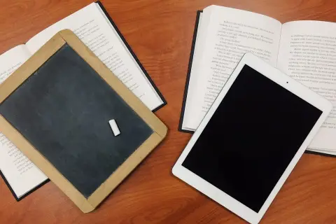 Tablica, książka i tablet na drewnianym stole. Czy postać literacka może istnieć bez konfliktu wewnętrznego?