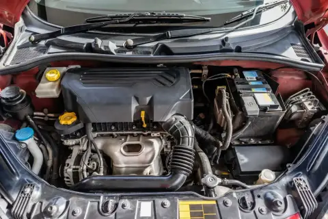 Silnik samochodu z widocznym zbiorniczkiem płynu chłodniczego. Gdzie jest czujnik temperatury w samochodzie? Zazwyczaj znajduje się w pobliżu termostatu lub w bloku silnika.