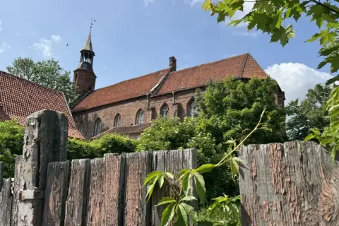 Stary, drewniany płot i ceglany kościół z wieżą w malowniczym mieście na Kociewiu.