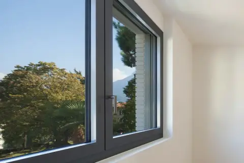 Finestra in alluminio con vista su alberi e montagne. Utile per chi cerca come regolare vecchi infissi in alluminio.