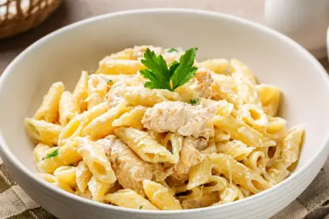 Penne z kurczakiem w kremowym sosie, udekorowane natką pietruszki. Pyszne danie, które zadowoli każdego miłośnika włoskich smaków.