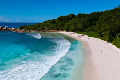 Rajska plaża z turkusowym oceanem indyjskim, białym piaskiem i bujną zielenią.