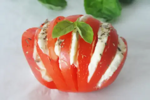 Tomate farcie d'une délicieuse recette avec mozzarella, garnie de basilic frais et d'herbes. Une bouchée d'été parfaite.