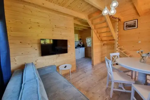 Przytulne wnętrze domku w stylu katy rybackie hotel. Drewniane ściany, kanapa, stół z krzesłami i schody na piętro.