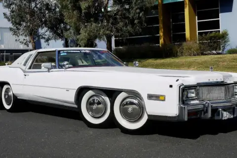 Biały Cadillac Eldorado z podwójnymi kołami z przodu i z tyłu. Ten niezwykły samochód ma aż cztery osie, co czyni go wyjątkowym na drodze.