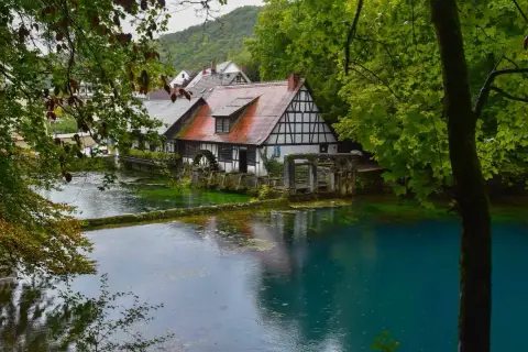 Ein Fachwerkhaus am kristallklaren Wasser, umgeben von üppigem Grün. Ein idyllischer Ort, einer der vielen Geheimtipps Deutschland Natur.