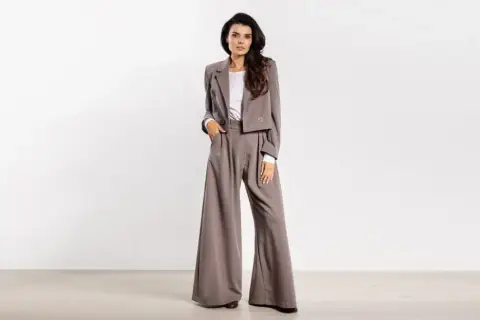 Elegancki strój kobiecy do filharmonii: krótka marynarka i szerokie spodnie w odcieniu taupe.