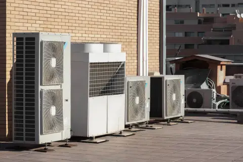 Rząd jednostek zewnętrznych klimatyzacji i pomp ciepła na dachu. Pomaga to zrozumieć, jak obliczyć potrzebną moc pompy ciepła.