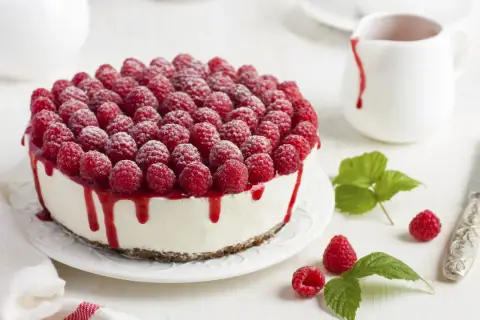 Ein köstlicher Kuchen ohne Backen, bedeckt mit frischen Himbeeren und Himbeersauce.