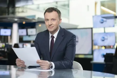 Krzysztof Górlicki, dziennikarz, w studiu telewizyjnym. Jego życiorys to historia pasji do informowania.