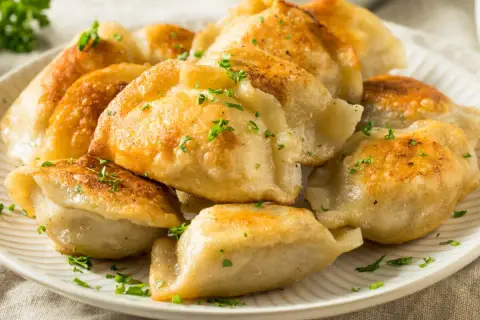 Złociste, rumiane pierogi z serem, posypane natką pietruszki. Idealne na obiad lub kolację, z pysznym farszem do pierogów z serem.