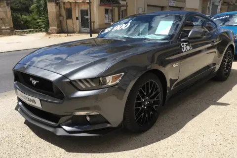 Szary Ford Mustang GT 5.0 z ceną 38 900 na szybie, gotowy do jazdy.
