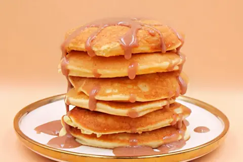 Stos puszystych naleśników polanych sosem. Czy pancake są zdrowe? Zależy od składników i dodatków!