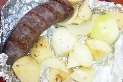 Kaszanka z grilla z cebulą w folii aluminiowej, gotowa do pieczenia. Aromatyczne dodatki podkreślą smak.