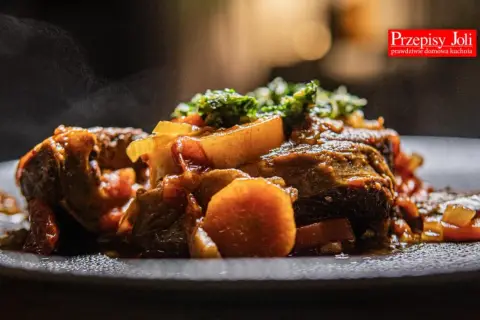 Pyszne, parujące ossobuco wołowe z warzywami na talerzu. Aromatyczne danie, które rozpływa się w ustach.