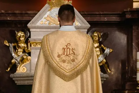 Kapłan w złotej kapie z symbolem IHS. Złote aniołki po bokach ołtarza. Zastanawiasz się, ile trwa msza?