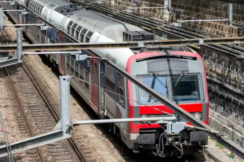 Pociąg RER A w Paryżu na torach, z widocznymi elementami infrastruktury kolejowej.