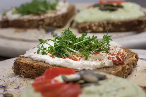 Pyszne, zdrowe pinchos na ciemnym pieczywie z serkiem, rukolą i pomidorem. Idealne na lekki posiłek.