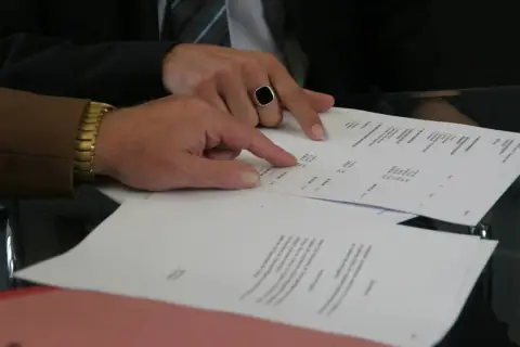 Dwaj mężczyźni analizują dokumenty, jeden wskazuje palcem na wypowiedzenie umowy najmu wzór przez wynajmującego.