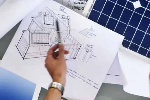 Rysunek domu z panelami fotowoltaicznymi na dachu i obok panel słoneczny. Projekt uwzględnia kąt nachylenia paneli fotowoltaicznych.