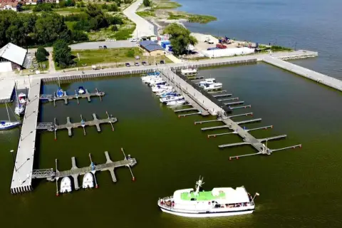 Widok z lotu ptaka na port w Krynicy Morskiej z licznymi łodziami i żaglówkami przy pomostach.
