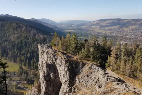 Widok z urwiska na Tatry i Zakopane. Ścieżka prowadzi przez las, pokazując, jak dojść na Nosal z Zakopanego.