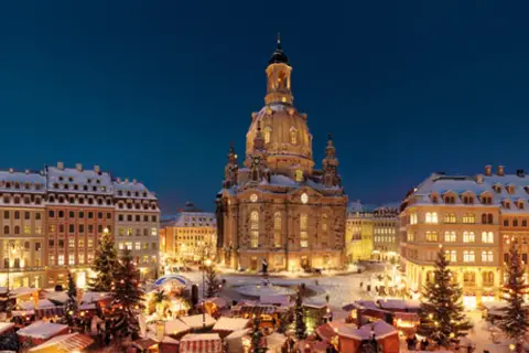 Śnieżny jarmark w Dreźnie. W tle Frauenkirche, po bokach oświetlone kamienice i choinki.