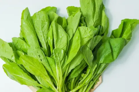 Ein Bündel frischer, grüner Blätter, die an Spinat erinnern. Dieses Blattgemüse ist ein Beweis dafür, wie gesund spinat gesund ist.