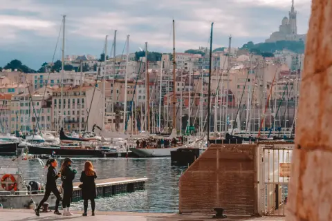 Widok na port w Marsylii z żaglówkami i budynkami w tle.