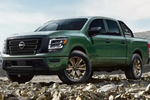 Zielony Nissan Titan z brązowymi felgami na kamienistym podłożu, gotowy na przygodę w górach.