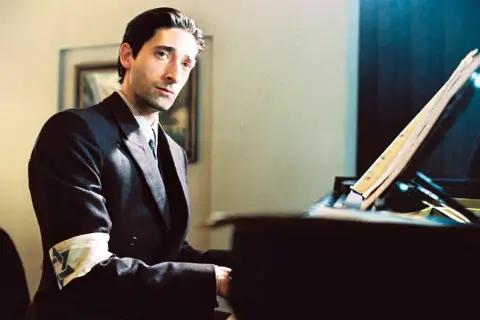 Adrien Brody gra na pianinie w filmie "Pianista", jednym z filmów Polańskiego alfabetycznie. Na ramieniu ma opaskę z gwiazdą Dawida.