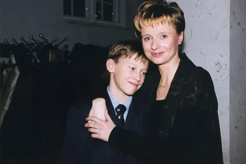 Uśmiechnięty Mateusz Matczak, syn Pieńkowskiej, w garniturze, przytulony do mamy.