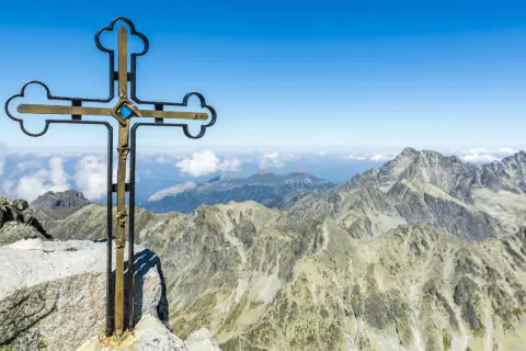 Krzyż na szczycie Gerlach bez przewodnika. Majestatyczne Tatry rozciągają się pod błękitnym niebem.