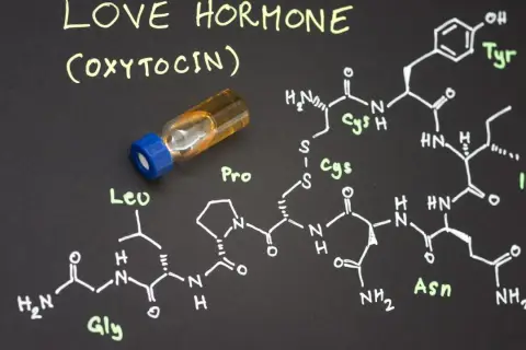 Struktura chemiczna oksytocyny, hormonu miłości, obok fiolki z płynem.