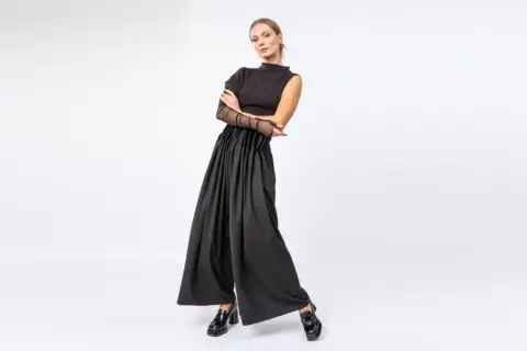 Elegancka stylizacja do teatru: czarny top z siateczkowymi rękawami i szerokie spodnie z wysokim stanem.