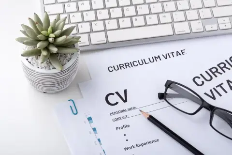 Na biurku leżą dokumenty CV, klawiatura i okulary. To miejsce pracy, gdzie liczy się wykształcenie i doświadczenie.