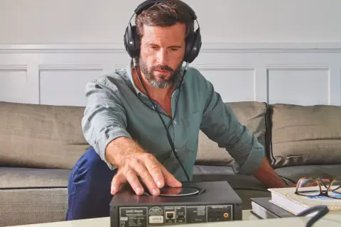 Mężczyzna w słuchawkach reguluje urządzenie audio, sprawdzając jego impedancję słuchawek.