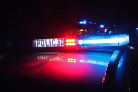 Policyjne światła błyskają w ciemności, sygnalizując sytuację wymagającą obrony koniecznej.