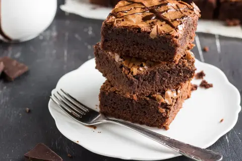 Stos puszystych brownie na talerzyku, idealne na zdrowe przekąski. Szukasz ciasta fit przepisy? Oto one!