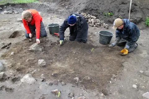 Osoby prowadzą archeologia studia, ostrożnie badając ziemię i kamienie.