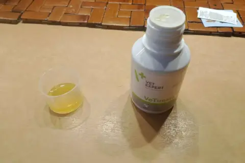 Płynna zawiesina **Vetussin** w kieliszku dozującym i butelce.