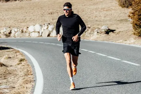 Jan Frodeno läuft auf einer Straße, seine leuchtend orangen Jan Frodeno Schuhe sind gut sichtbar.